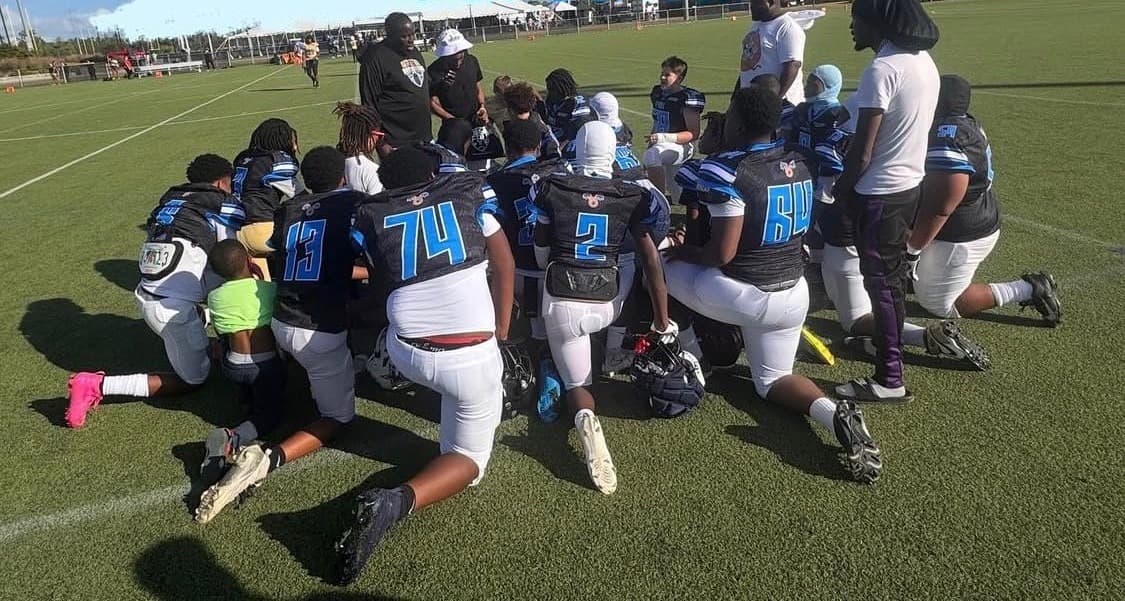 FBU Team Carolina athletes and coaches taking a knee together on the field