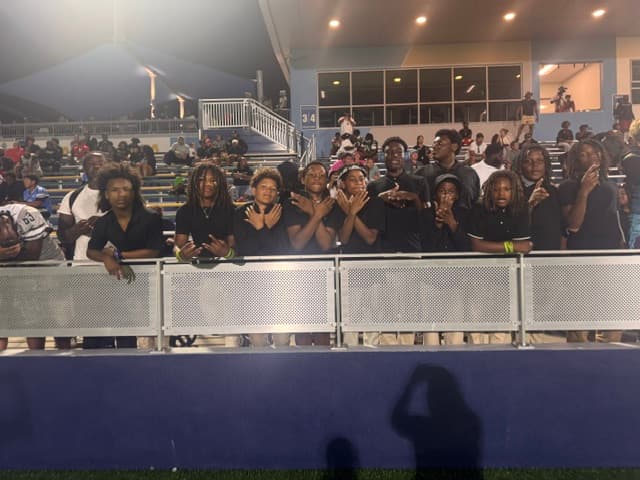 FBU Team Carolina athletes lined up along the rail under the lights, cheering on their teammates