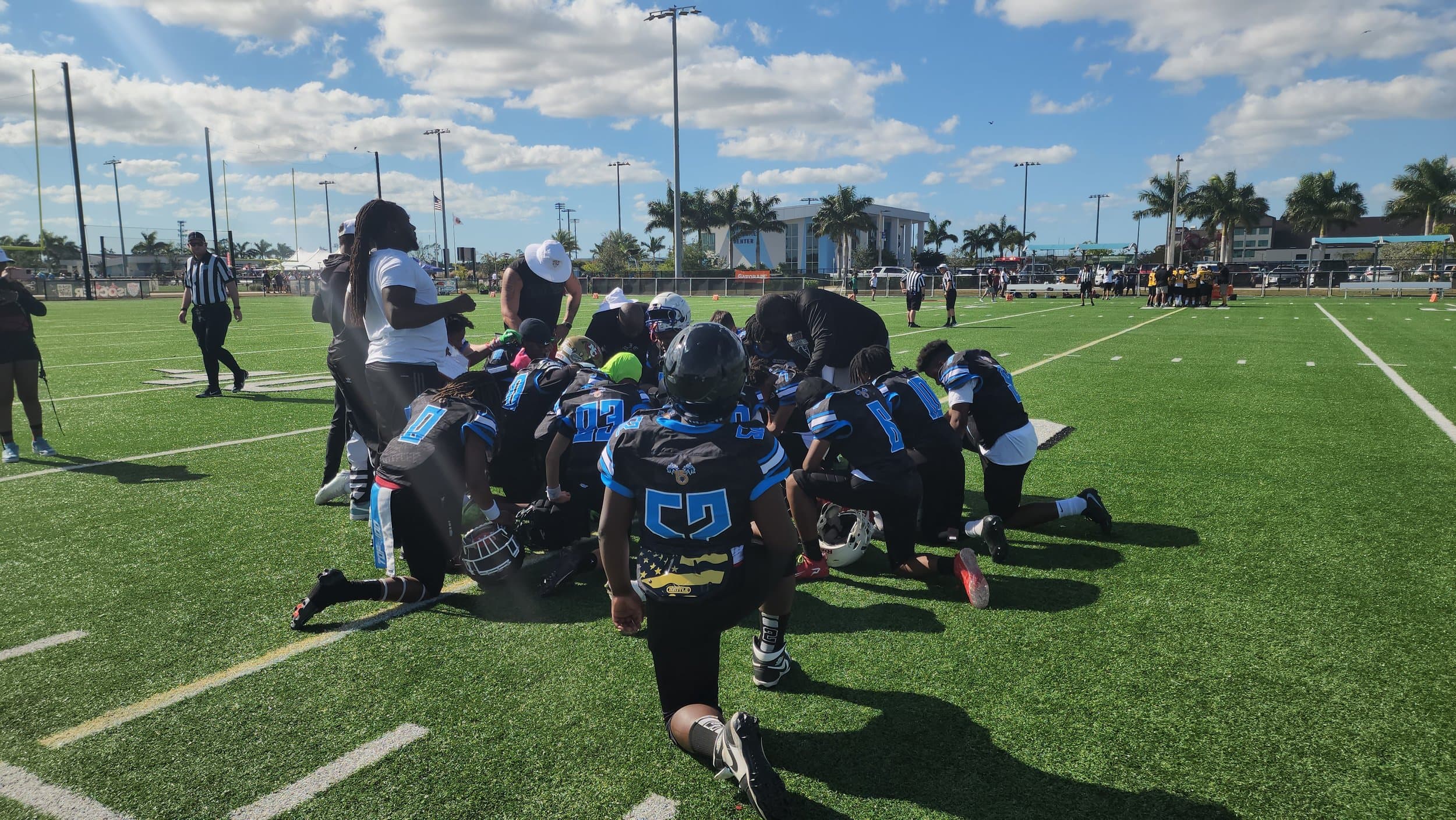 FBU Team Carolina athletes and coaches taking a knee together on the field