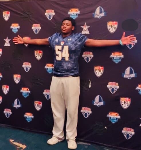 Landrey Thompson, arms outstretched, in his number 54 jersey in front of the FBU event backdrop