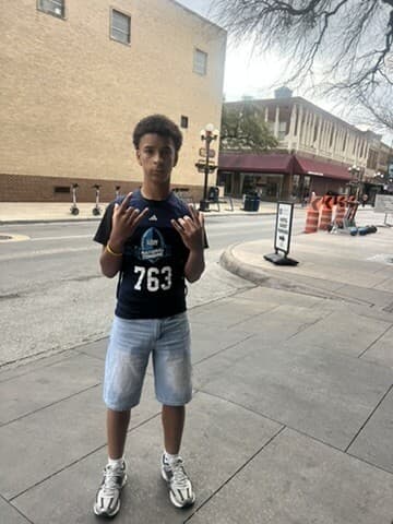 Vonzelle Brown II in his number 763 Navy National Combine shirt, throwing up a hand sign on a San Antonio street